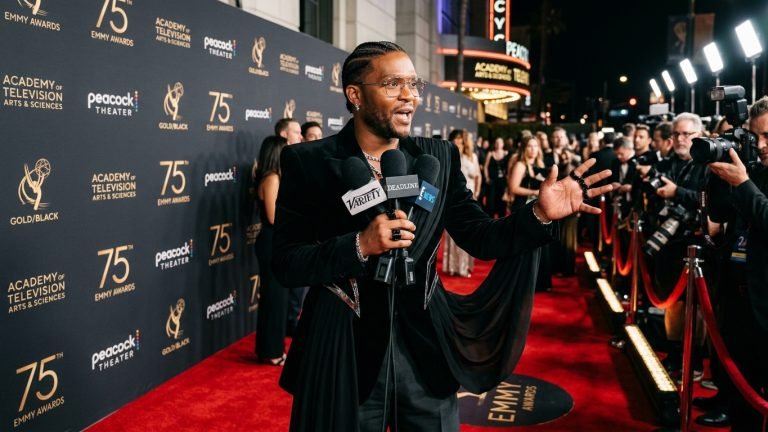 Celebrity stylist Law Roach speaking into press microphones on the Emmy Awards red carpet